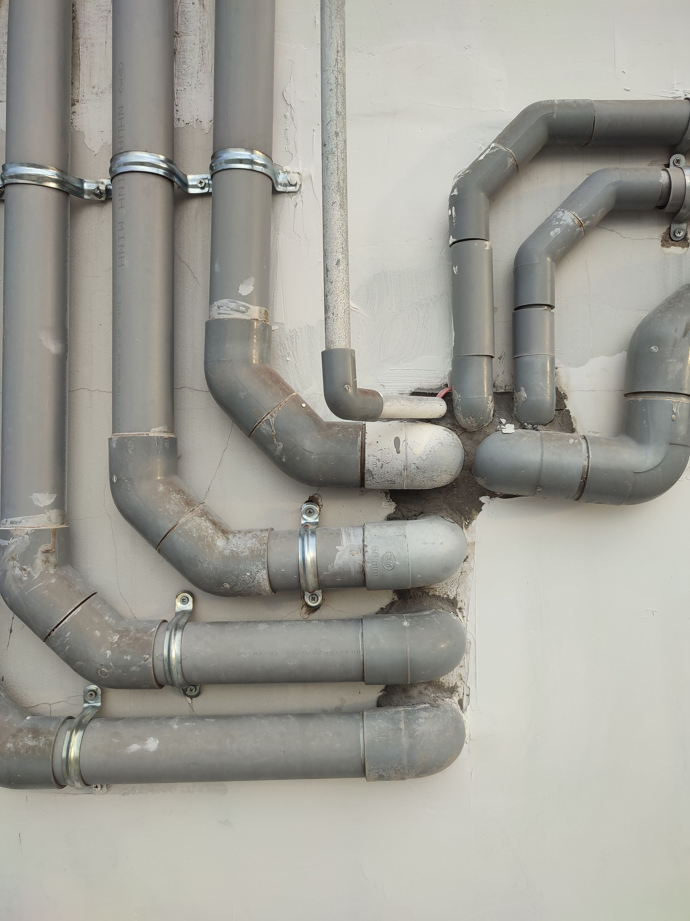 Verstopfung Rohrreinigung Graue Abwasserrohre an einer weissen Wand – Rohrreinigung bei Verstopfung durch SOS Gebäudetechnik
