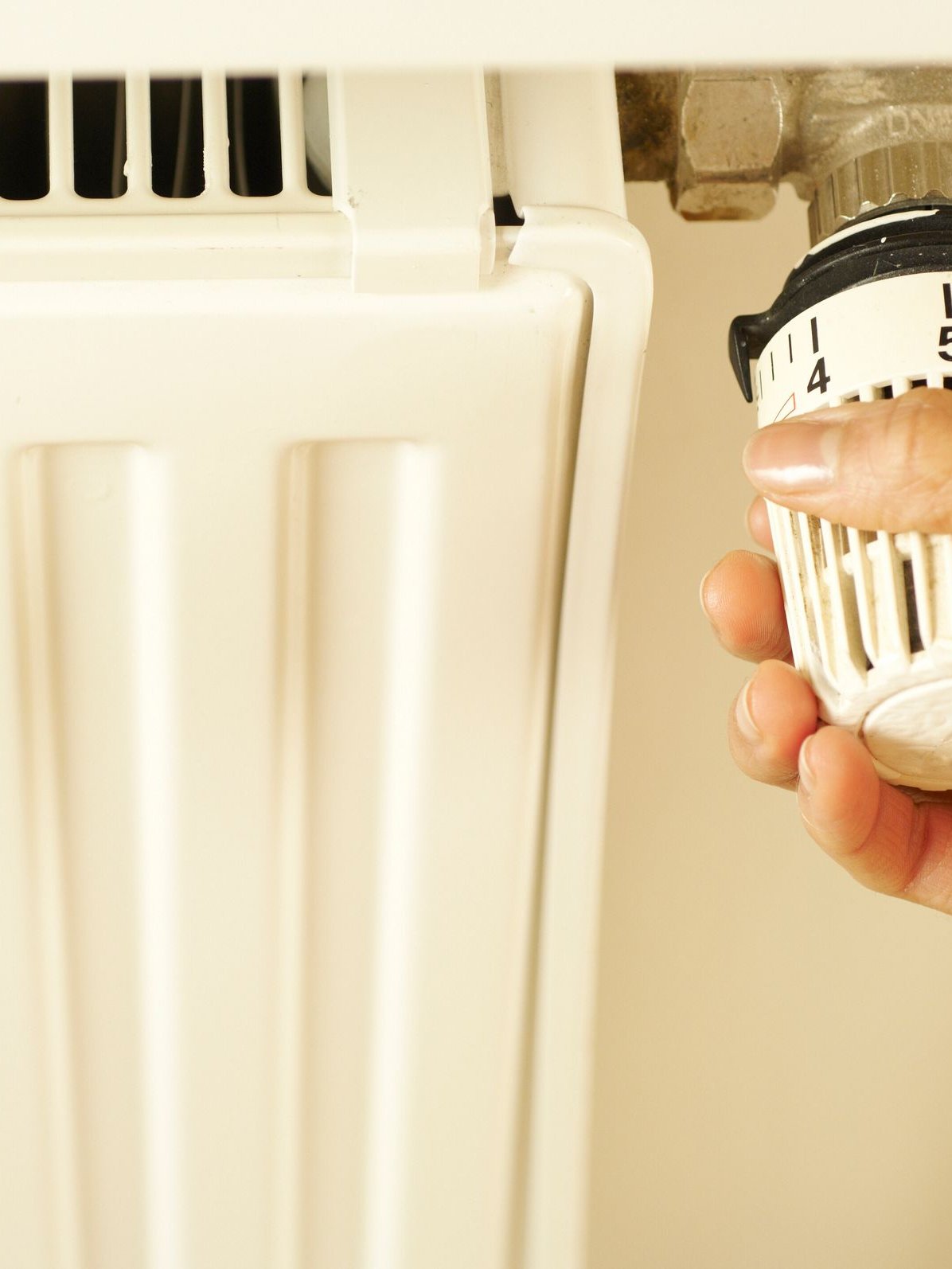 Heizungsnotdienst Hand dreht am Thermostat eines Heizkörpers – Heizungsnotdienst von SOS Gebäudetechnik