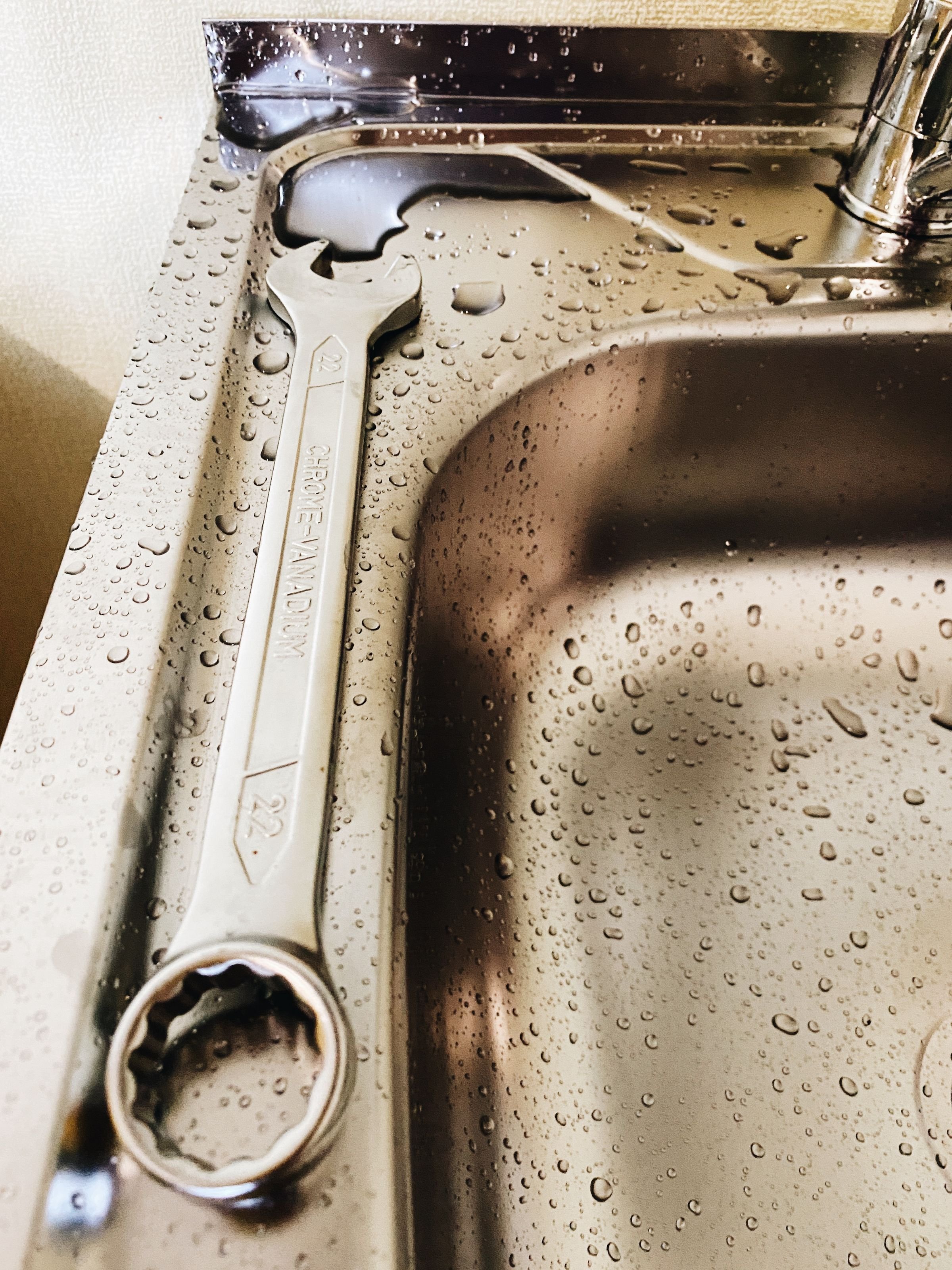 Sanitär-Notdienst Schraubenschlüssel in einem Spülbecken mit Wassertropfen – Sanitär-Notdienst von SOS Gebäudetechnik